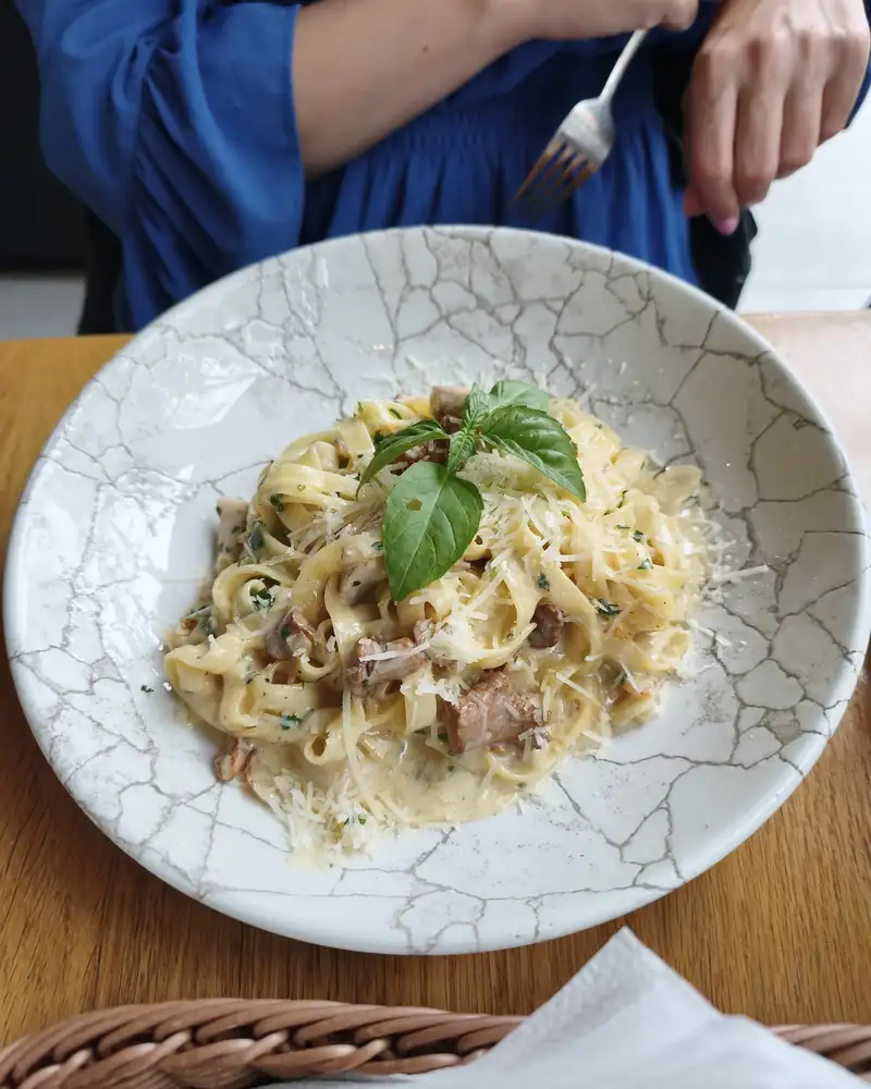 Talerz tagliatelle z bazylią na drewnianym stole