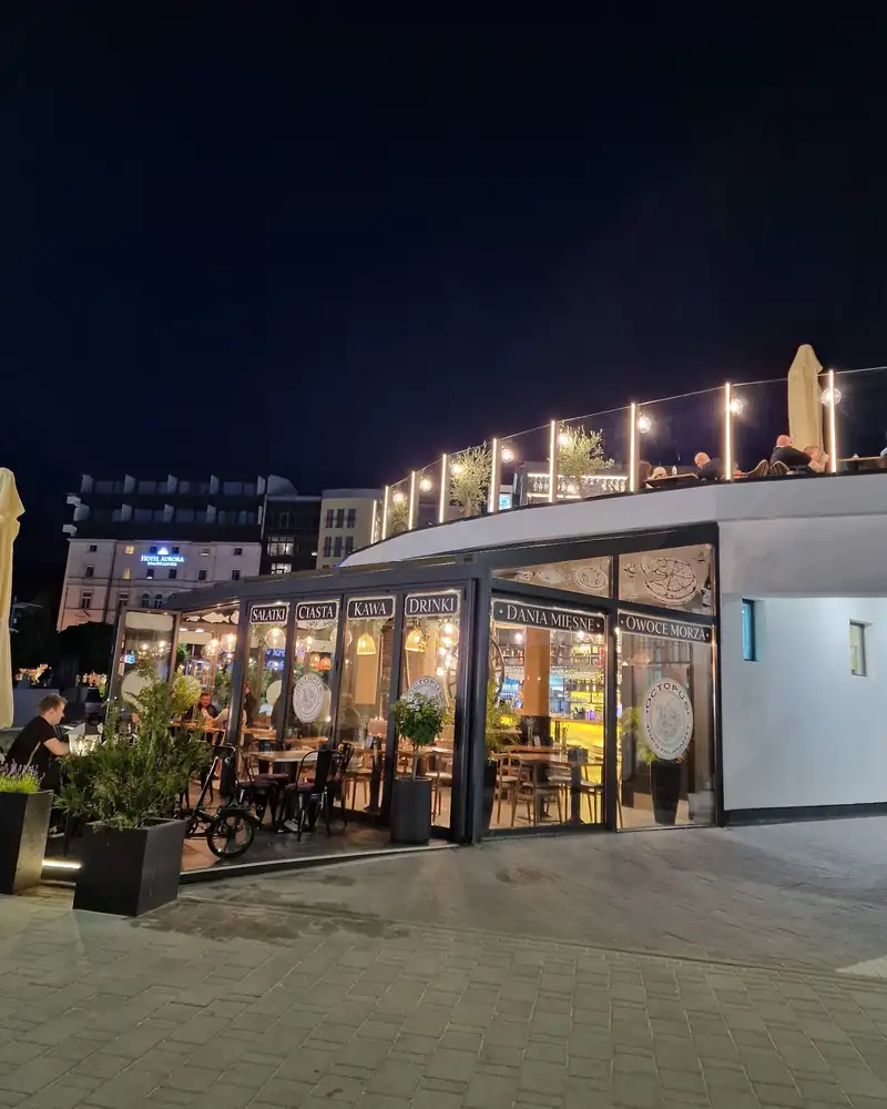 Przeszklony pawilon restauracji nocą, ze światełkami na dachu